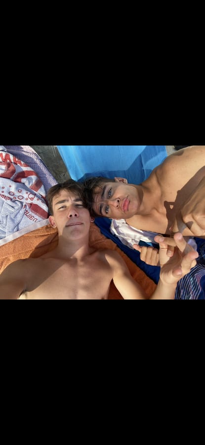 Deux amis allongés sur des serviettes de plage, en pleine journée ensoleillée.