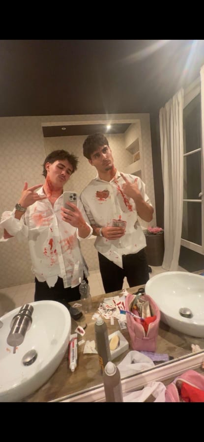 Deux amis déguisés, chemises tachées de faux sang, pris en photo dans un miroir.